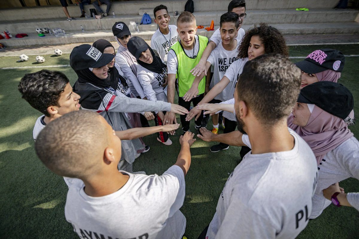 Young people in a team huddle joining hands together