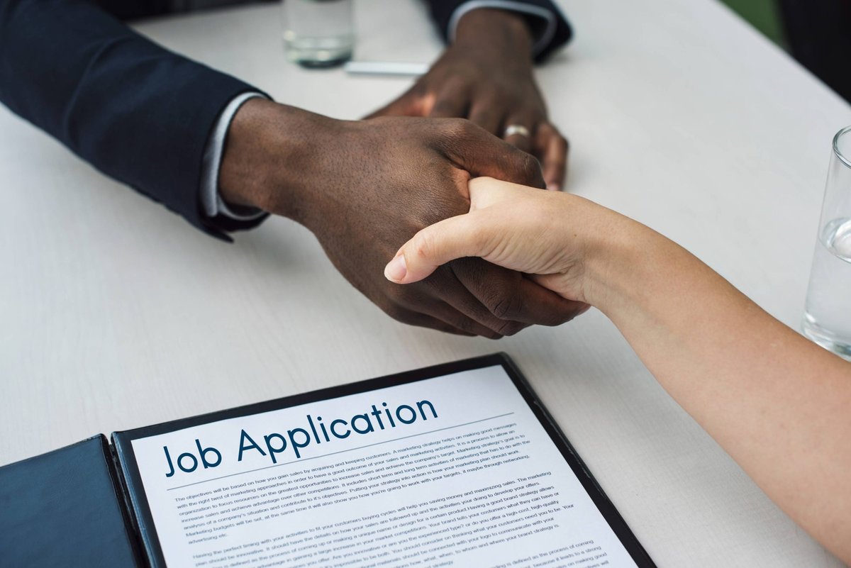 A handshake over a job application during a mentoring meeting