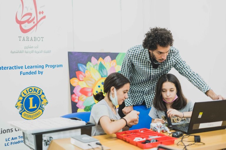 Young people learning hands-on at a laptop with a mentor