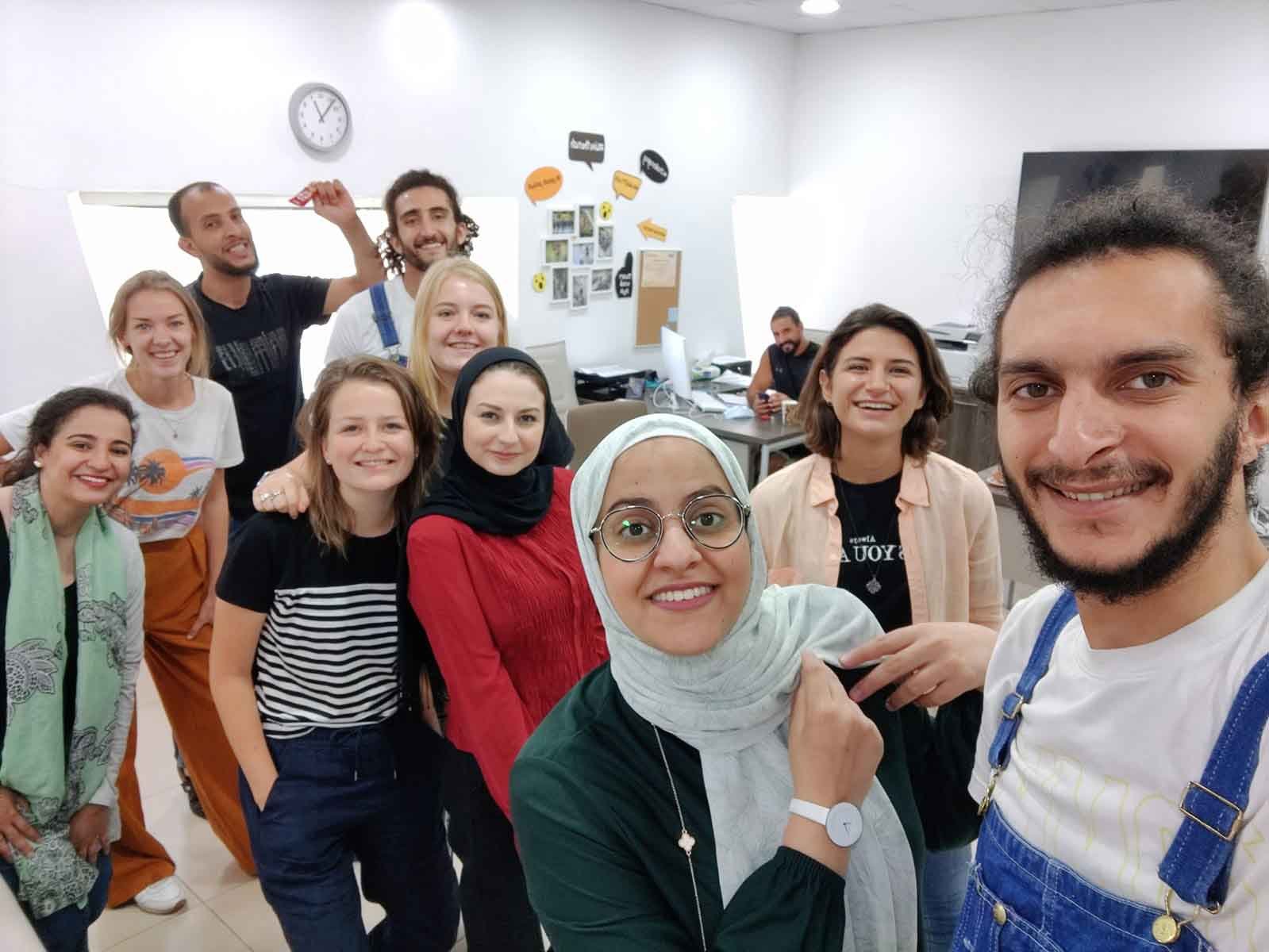 A diverse team of young people gathered together smiling in their workspace